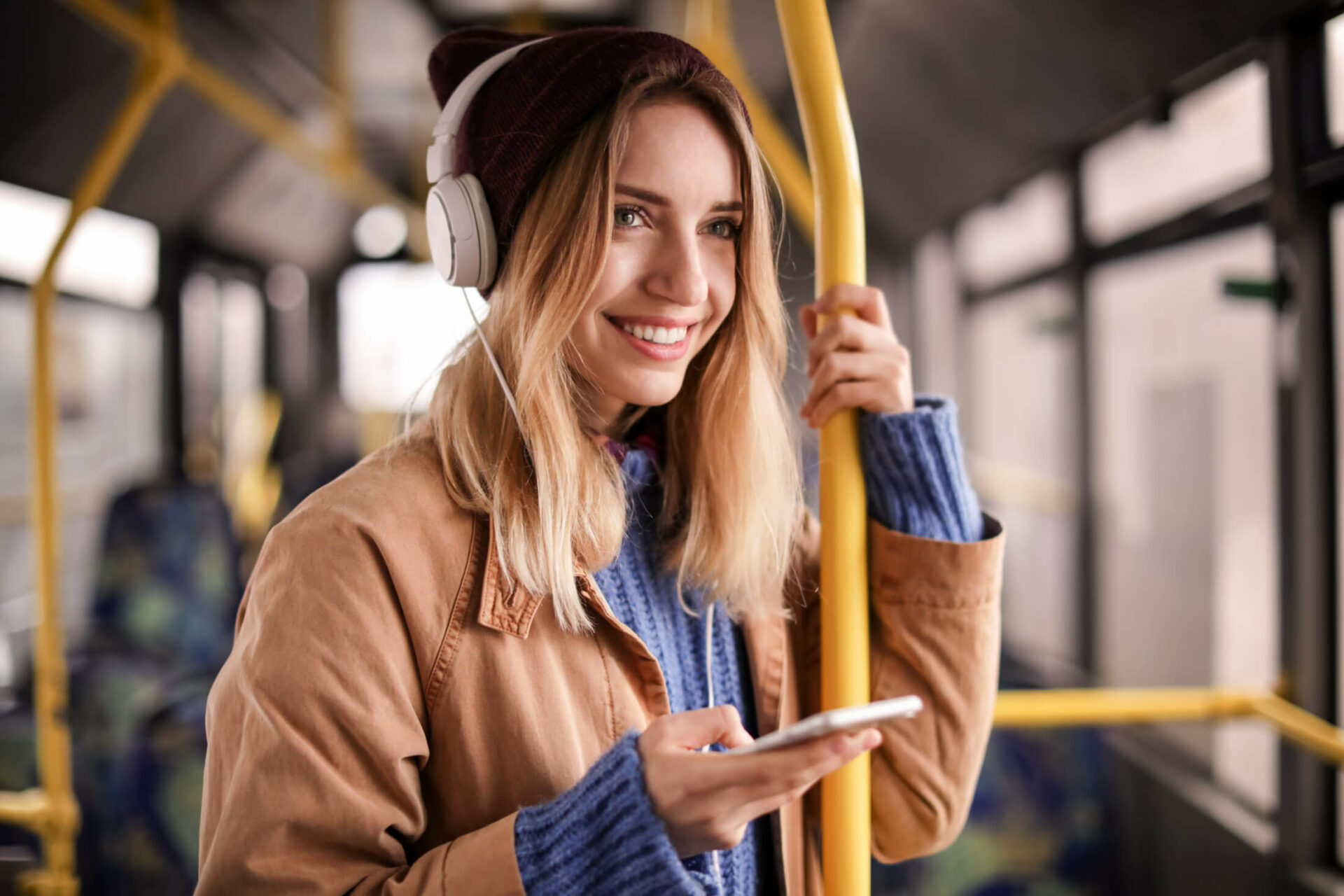 Junge Frau steht mit Smartphone im Bus